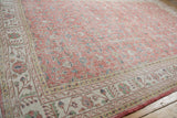 Distressed blush field with faded floral blossoms and ivory geometric vine main border.