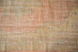Distressed vintage Oushak rug pile with visible foundation, muted rose, saffron, and sage green.