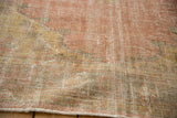 Distressed Oushak carpet texture revealing worn knot heads and foundation in rose, saffron, beige.