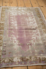Distressed vintage Oushak rug, worn pale violet pile revealing foundation, bronze leaf border.
