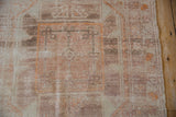 Close-up on a distressed Oushak medallion in dusty rose, mauve, and tangerine orange.