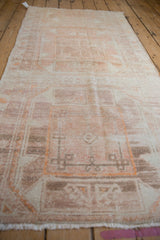 Angled view down the length of a distressed Oushak runner showing its heavy abrash and faded medallions.