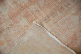 A corner of the distressed Oushak rug folded back to reveal the hand-knotted foundation.