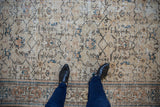 Vintage distressed Oushak carpet featuring soft beige tones, sky blue palmettes, and geometric vinery.