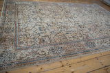 Distressed Oushak carpet with beige field, blue palmettes, pale brown cartouche and snowflake border.