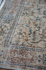 Distressed vintage Oushak rug showing faded beige field, blue palmettes, and geometric border.