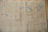 Distressed Oushak pile detail with muted beige, blue, and coffee brown patterns and secured selvage.
