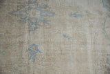 Distressed vintage Oushak carpet detail with worn pile and faded blue palmettes.