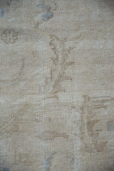 Distressed Oushak pile showing beige, ivory tones and exposed foundation.