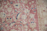 Distressed Turkish Sparta rug with faded cochineal pink floral vinery and exposed foundation.