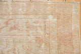 Distressed Oushak rug with prominent foundation showing through, antique ivory, dusty rose tones.