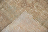 Distressed vintage Oushak rug corner, showing worn pile and exposed foundation.