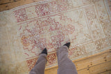 Distressed Oushak rug runner with faded cherry red geometric patterns on an aged ivory field with abrashes.