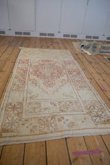 Faded cherry red stepped pattern on a distressed ivory vintage Oushak rug runner.