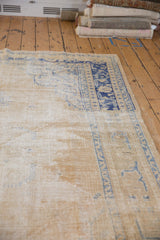 Distressed vintage Oushak carpet with worn texture, faded cream, and cobalt blue patterns.