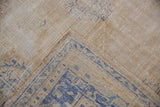 Distressed vintage Oushak carpet corner, worn pile exposing foundation, and cobalt blue pattern.