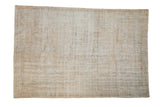 Vintage distressed Oushak carpet with a faded floral medallion on an open field of cream, ivory, and beige.