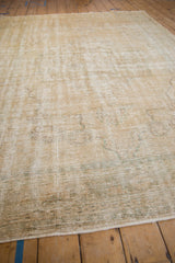 A low angle view across the distressed, low-pile texture of a vintage Oushak carpet.