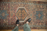Distressed vintage Karaja rug: central intricate medallion with ribboned geometric motifs.