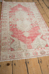 Textured view of vintage distressed Oushak rug with dusty raspberry palmettes and ivory ground.
