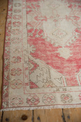 Distressed Oushak rug with dusty raspberry, ivory floral leaves, and softened texture.