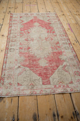 Distressed Oushak rug pile showing dusty raspberry red and antique ivory floral motifs.