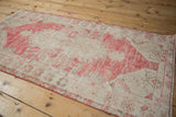Vintage distressed Oushak rug detail showing dusty raspberry red and cream hues with worn pile.