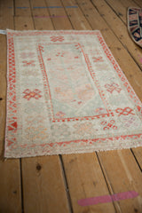 Distressed Oushak rug pile with faded sea foam green, ivory, and tangerine plant motifs.