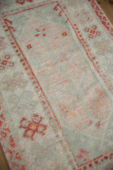 Vintage distressed Oushak rug's worn pile, showcasing softened sea foam green and tangerine motifs.
