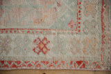Distressed Oushak rug corner detail, highlighting sea foam green, tangerine, and mauve floral borders.