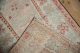 Distressed vintage Oushak rug showing pile wear, hand-knotted back, and secured side edge.