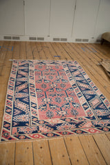 Vintage Distressed Melas rug corner, pale cherry and navy geometric hook-and-latch motifs, fringed.