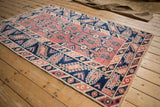 Distressed navy and pale cherry red geometric patterns on Melas rug's machine-bound side.