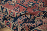 Distressed Melas rug with abrashed cherry red ground and navy geometric motifs.