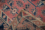Distressed Melas rug's folded corner with cherry red field, reverse view, and machine-bound selvage.