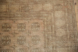 Distressed Afghani Bokhara rug corner detail with pale copper gul motifs and patterned borders.