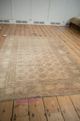 Distressed Afghani rug's elephant footprint gul and pinwheel motifs in pale copper and ivory.