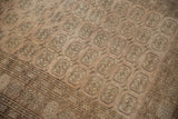Elephant gul and pinwheel motifs on distressed Afghani Bokhara rug in pale copper-brown.