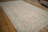 Distressed pile of a vintage Sparta rug, with faded rose, ivory, and blue.