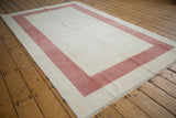 Textural distressed vintage Oushak rug corner with faded ivory and raspberry red.