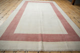 Faded raspberry red border, ivory field, and detailed fringe of a distressed Oushak rug.