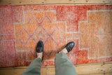 Distressed Kurd rug runner detail, featuring red, orange, violet patterns, and worn texture.