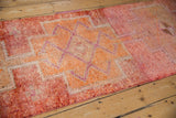Distressed pile texture of the Kurd runner with geometric motifs in raspberry and orange.