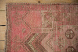 Distressed vintage Daulatabad rug corner with blush pink, camel patterns, and visible wavy fringe.