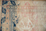 Distressed Kayseri carpet corner, navy blue border contrasting with faded ivory and rose patterns.