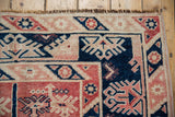 Distressed Melas rug's navy, cherry red geometric patterns, with fringe and selvage.