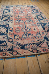 Distressed vintage Melas rug detail: pale cherry red field and navy hook and latch motifs.