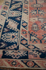 Softened pile of distressed vintage Melas rug with navy geometric and pale cherry red patterns.
