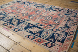 Distressed vintage Melas rug corner with machine bound selvage and geometric navy, red patterns.