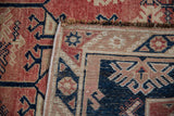 Vintage Distressed Melas rug corner: worn cherry red pile, navy patterns, machine-bound selvage.